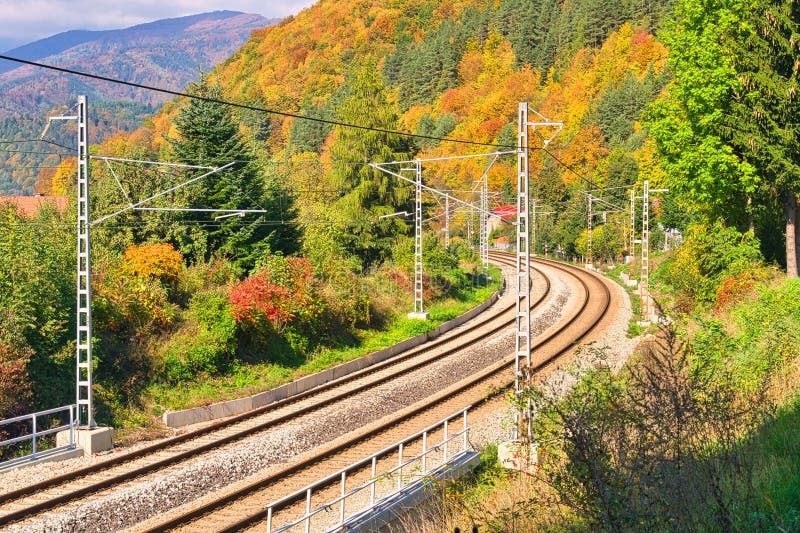 Electrified railway track near the village of Stankovany during autumn, Europe, Slovakia. Fall coloured trees under Mala Fatra mountains. Electrified railway track near the village of Stankovany during autumn, Europe, Slovakia. Fall coloured trees under Mala Fatra mountains.