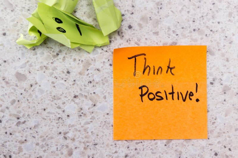 Concept for a positive attitude with small crumbled up sad faces and a note with the phrase think positive. Concept for a positive attitude with small crumbled up sad faces and a note with the phrase think positive