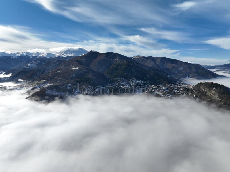 A stunning winter landscape featuring snow-covered mountains and vast, moody clouds above them. A stunning winter landscape featuring snow-covered mountains and vast, moody clouds above them