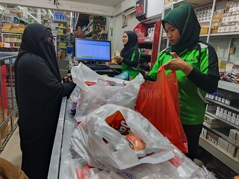 Poso, Indonesia - July 2, 2023: Muslim woman is shopping or paying for groceries in supermarket. Poso, Indonesia - July 2, 2023: Muslim woman is shopping or paying for groceries in supermarket.