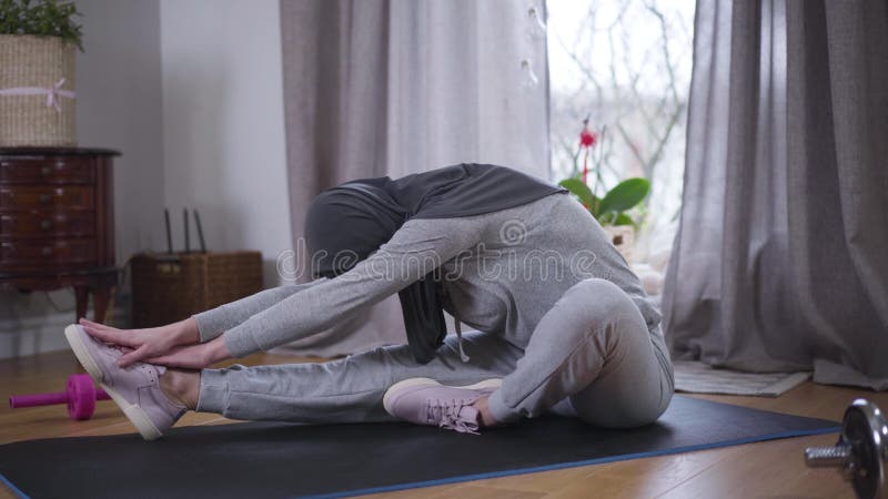 穆斯林苗条女子弯腰在瑜伽垫上试图用手触足的侧视 运动型年轻女性 股票视频