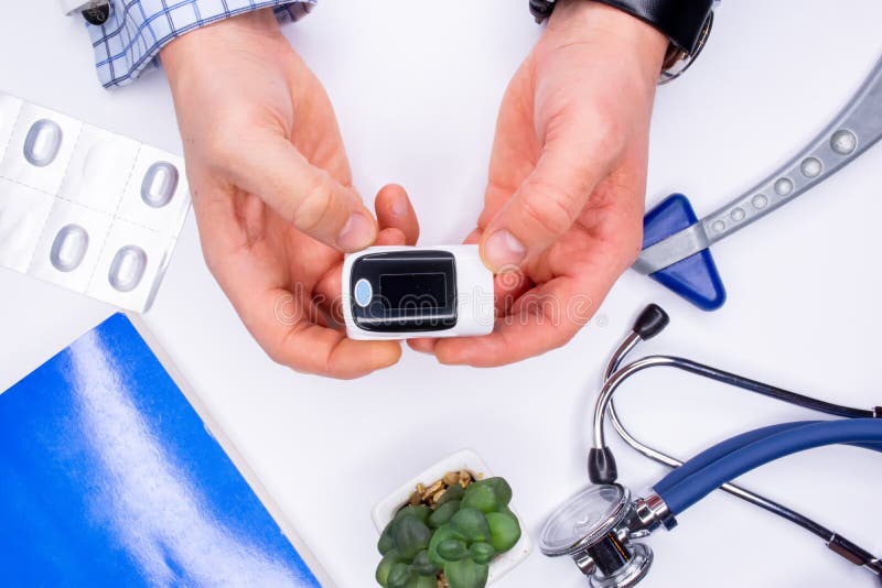 医生、护士或身穿白色无菌外套的医护人员将脉搏血氧仪戴在手指上，检查血液的氧饱和度 免版税库存照片