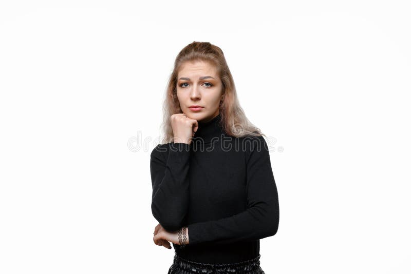 穿着休闲服、悲伤而无聊的年轻女性，双手低头，冷眼旁观着相机里的白色背景 库存图片