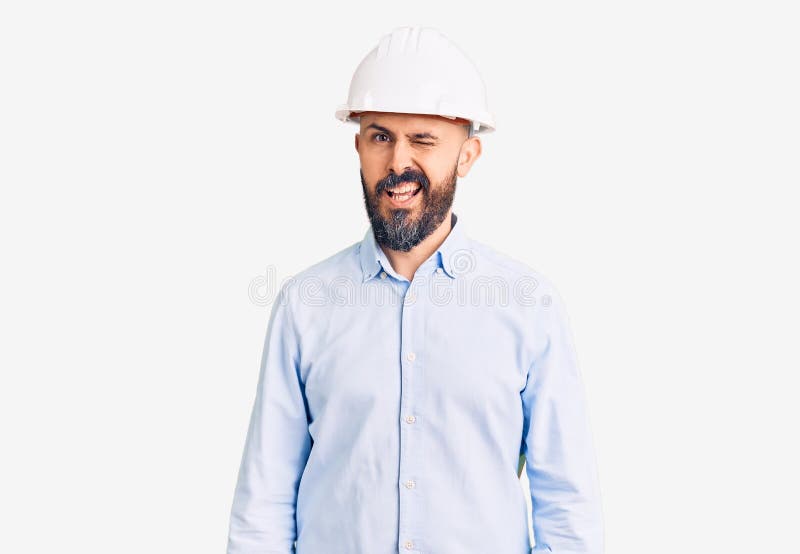 穿着建筑师精装帽的年轻英俊男子，面带性感的欢快表情和快乐的面孔，看着镜头 免版税库存照片