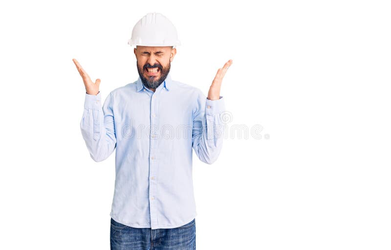 穿着建筑设计精装帽的年轻英俊男子，用双臂举起和闭眼尖叫，庆祝疯狂和疯狂的成功 免版税库存照片