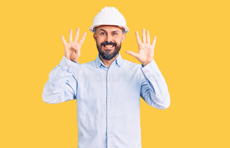 穿着建筑设计精装的年轻英俊男子露面并指着9号手指，同时微笑着自信而快乐 库存图片