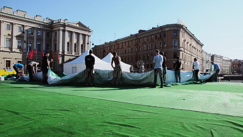 建立事件的人阶段在街道上 工作者拿着巨大的绿色帐篷 晴朗