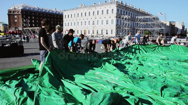 建立事件的人阶段在街道上 工作者运载巨大的绿色帐篷 晴朗