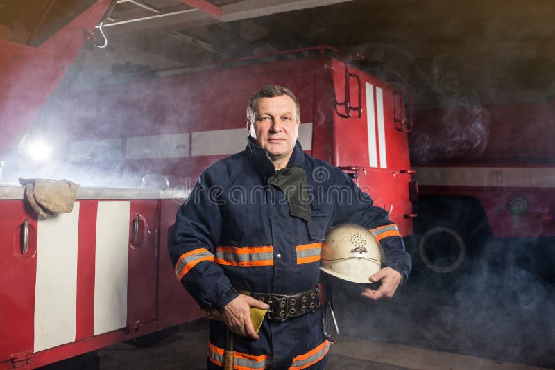 Fireman firefighter in action standing near a firetruck. Emergency safety. Protection, rescue from danger. Fireman firefighter in action standing near a firetruck. Emergency safety. Protection, rescue from danger.