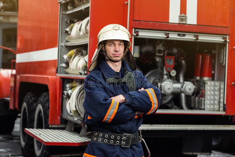 Fireman firefighter in action standing near a firetruck. Emergency safety . Protection, rescue from danger. Fireman firefighter in action standing near a firetruck. Emergency safety . Protection, rescue from danger.