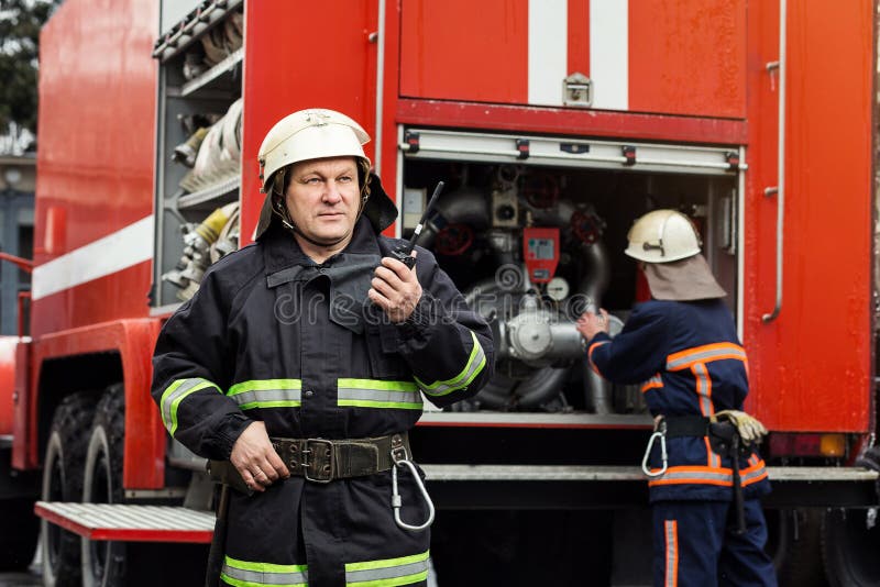 Fireman firefighter in action standing near a firetruck. Emergency safety. Protection, rescue from danger. Fireman firefighter in action standing near a firetruck. Emergency safety. Protection, rescue from danger.