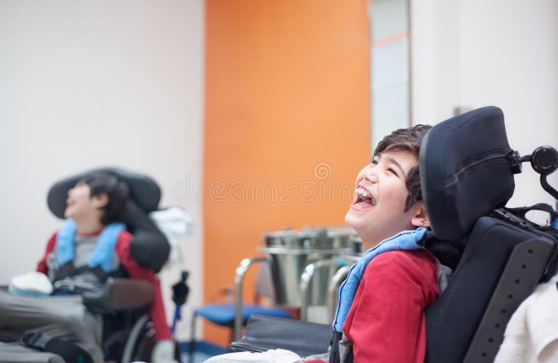 等待在医生的轮椅的愉快,微笑的失去能力的男孩 免版税库存照片
