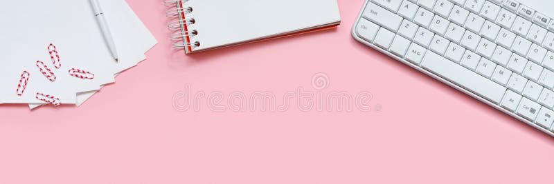 粉红色背景中的笔记本电脑、附件和笔 工作场所平铺 免版税库存照片