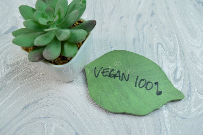 Concept of Vegan 100% write on sticky notes isolated on Wooden Table. Concept of Vegan 100% write on sticky notes isolated on Wooden Table