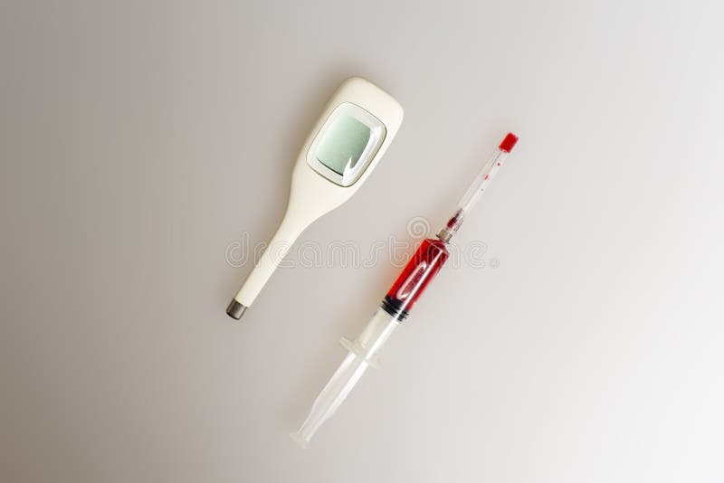 红色液体注射器及电子温度计 库存照片 红色液体注射器及电子温度计 库存照片
