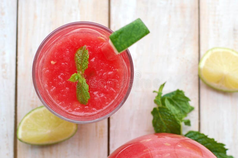 Healthy fresh smoothie drink from red watermelon, lime, mint and ice drift in glass with straw, overhead horizontal view. Healthy fresh smoothie drink from red watermelon, lime, mint and ice drift in glass with straw, overhead horizontal view