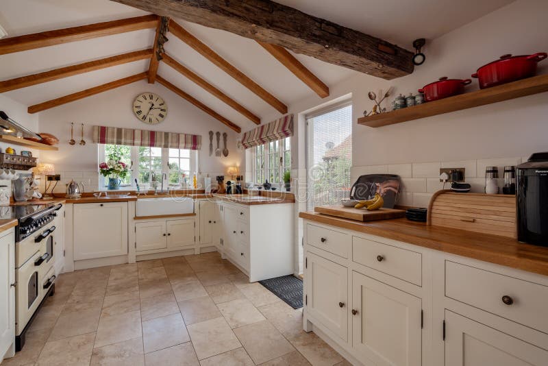 Hawkedon, England - August 15 2018: Fitted kitchen within historic grade 2 cottage with tiled floor and butler style sink. Hawkedon, England - August 15 2018: Fitted kitchen within historic grade 2 cottage with tiled floor and butler style sink