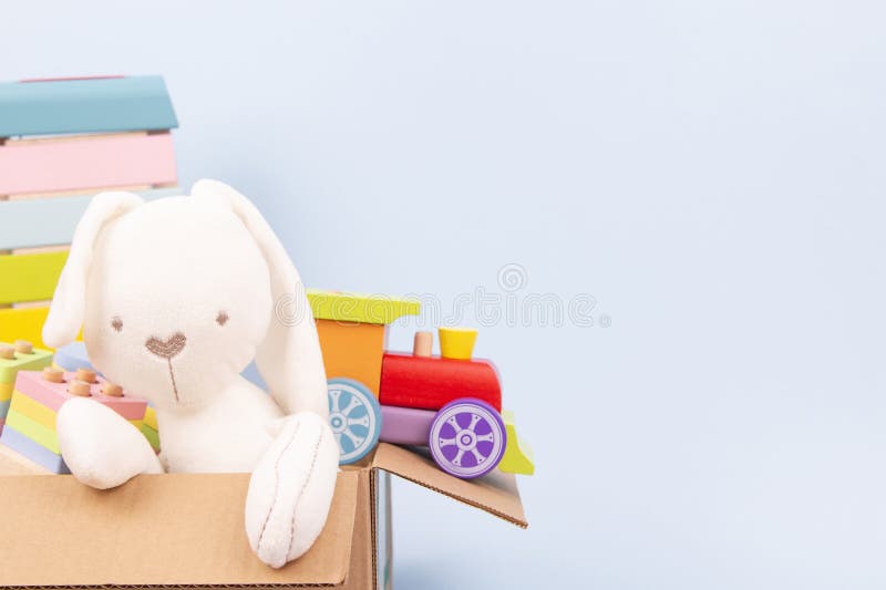 纸箱里的小孩玩具. 浅蓝色背景中带文本复制空间的白兔子和教育用木制玩具. 前 免版税库存照片