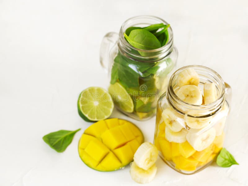 绿色菠菜鲕梨圆滑的人和香蕉芒果圆滑的人的成份在金属螺盖玻璃瓶
