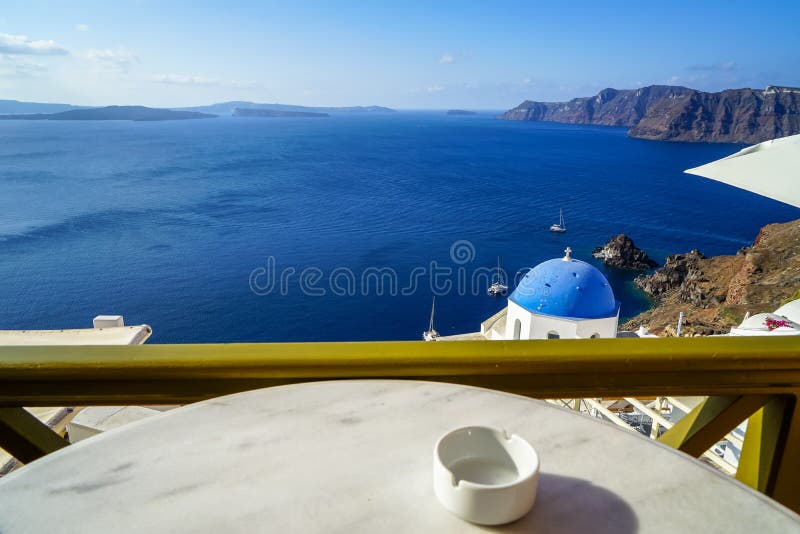 美丽的深蓝色爱琴海海洋全景海视图和蓝色教会屋顶从早餐咖啡店与白色大理石桌 库存照片 美丽的深蓝色爱琴海海洋全景海视图和蓝色教会屋顶从早餐咖啡店与白色大理石桌 库存照片
