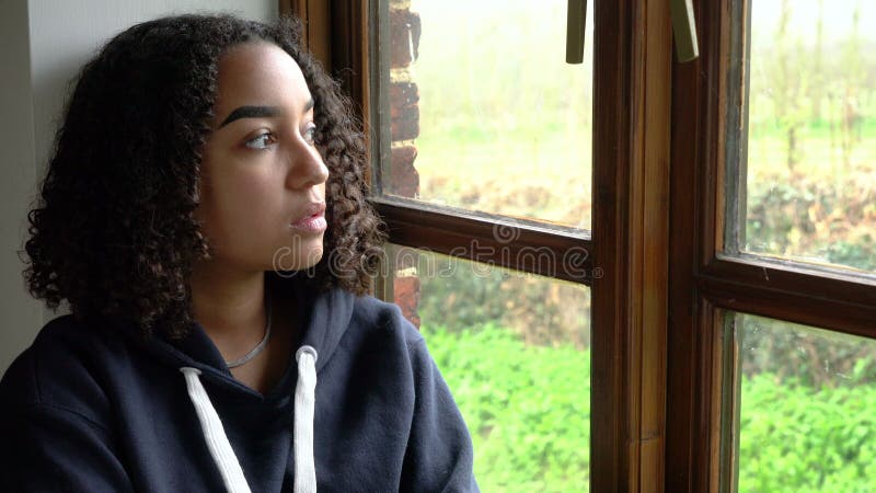 美丽的混合种族双种族非洲裔少女从窗外望去，看上去既悲伤又幸福