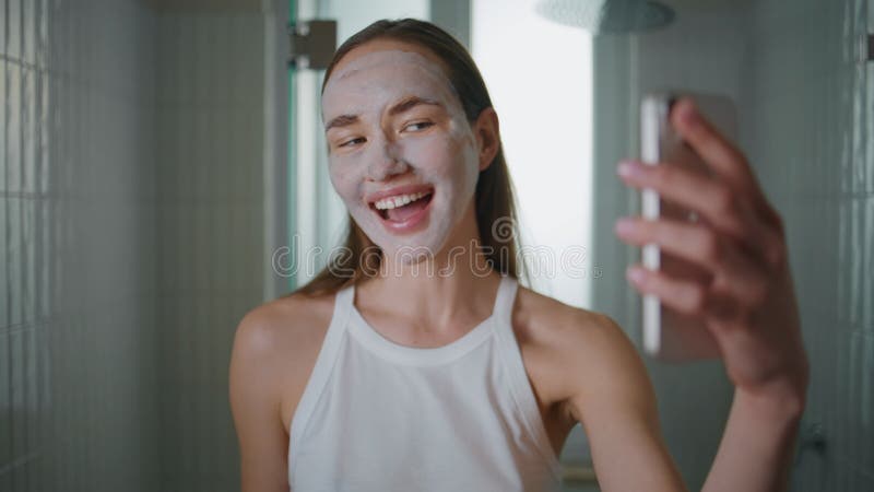 美女在浴室特写中录制带保湿面罩的智能手机视频. 影视素材