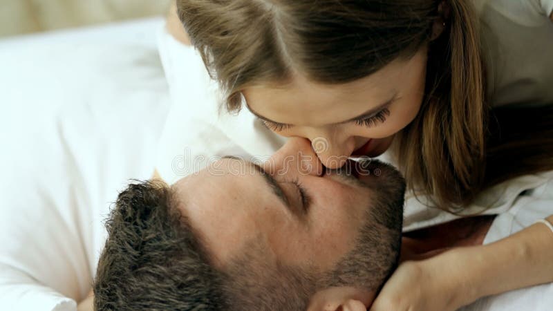 年轻美好和爱恋的夫妇特写镜头充当并且亲吻床在早晨 亲吻和拥抱他的可爱的人