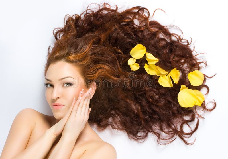 Close-up beautiful fresh luxury red-haired lady with yellow petals in her hair. Close-up beautiful fresh luxury red-haired lady with yellow petals in her hair