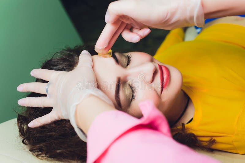 美容院的蜡胡子脱毛 接受面部摘除的年轻女性 美容师 免版税库存照片 美容院的蜡胡子脱毛 接受面部摘除的年轻女性 美容师 免版税库存照片