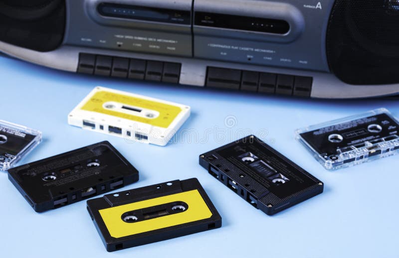 Old black retro cassette music audio tape recorder and retro cassette tape collection on blue background. Old black retro cassette music audio tape recorder and retro cassette tape collection on blue background