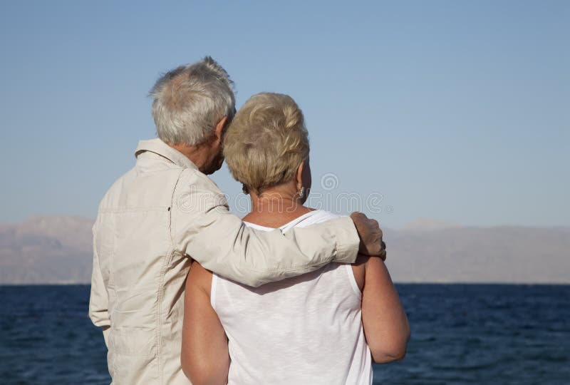 A retired couple lost in their thoughts as they watch the ocean. A retired couple lost in their thoughts as they watch the ocean