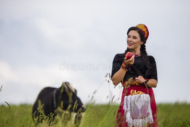 肉欲的白种人浅黑肤色的男人时尚画象俄国Kokoshnik的与面包圆环篮子 摆在反对在领域的母牛 库存照片 肉欲的白种人浅黑肤色的男人时尚画象俄国Kokoshnik的与面包圆环篮子 摆在反对在领域的母牛 库存照片