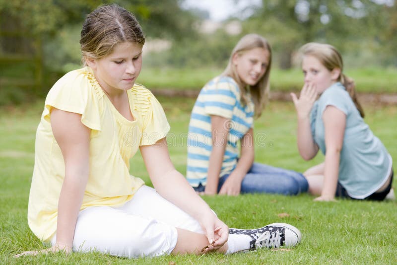 Two young girls bullying other young girl outdoors. Two young girls bullying other young girl outdoors.