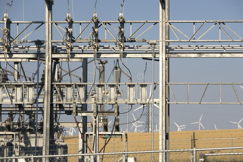 Power transformers in a wind turbine farm with windmills in the background. Power transformers in a wind turbine farm with windmills in the background