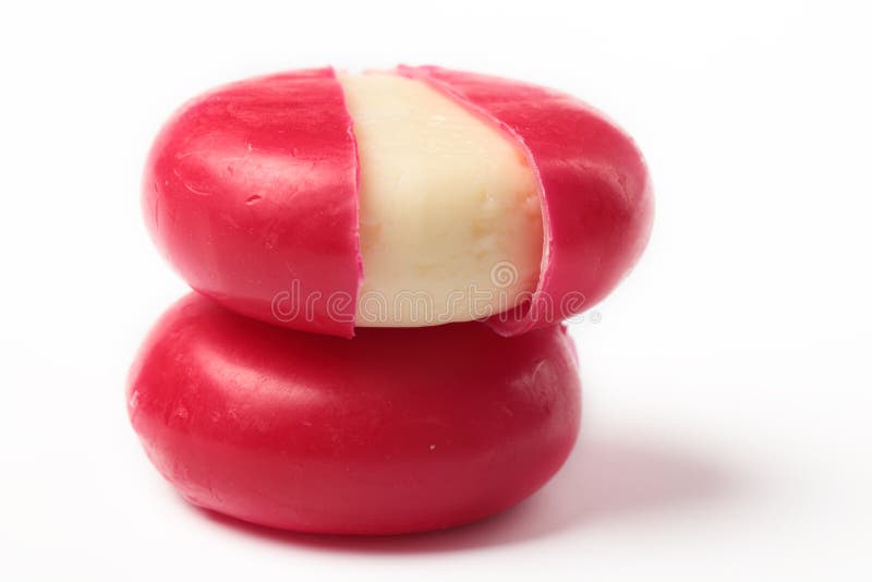 Two piece of cheese in red wax against white background. Two piece of cheese in red wax against white background