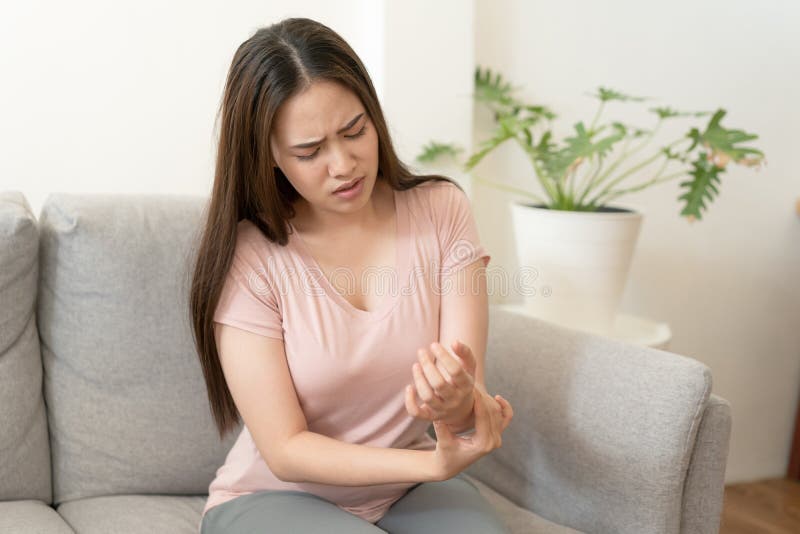 腕痛坐在沙发上的亚洲女孩 年轻女孩有痛性关节炎、健康和疾病概念 免版税图库摄影 腕痛坐在沙发上的亚洲女孩 年轻女孩有痛性关节炎、健康和疾病概念 免版税图库摄影