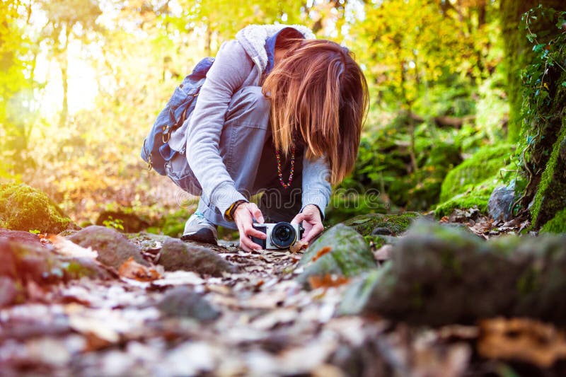 Nature photography. Photographer woman in the woods. A woman is by placing the camera on the ground to capture the beauty of nature in a forest. Autumn scenery. Passion for photography. Nature photography. Photographer woman in the woods. A woman is by placing the camera on the ground to capture the beauty of nature in a forest. Autumn scenery. Passion for photography.