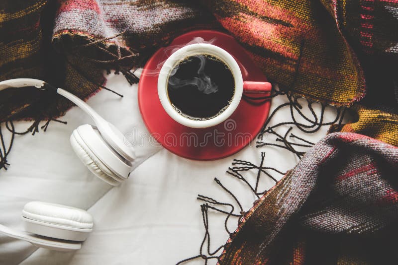 舒适冬天家庭背景，杯子热的咖啡用蛋白软糖，温暖在白色床上的被编织的毛线衣