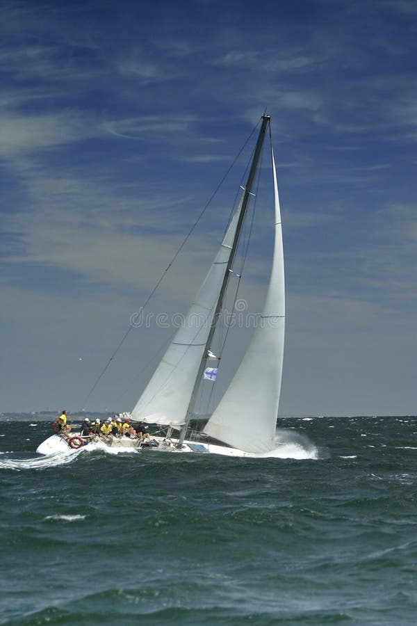 The large waves cover a sailing yacht. The team of a sailing yacht levels an inclination of a boat. Strong storm wind and large waves. The large waves cover a sailing yacht. The team of a sailing yacht levels an inclination of a boat. Strong storm wind and large waves