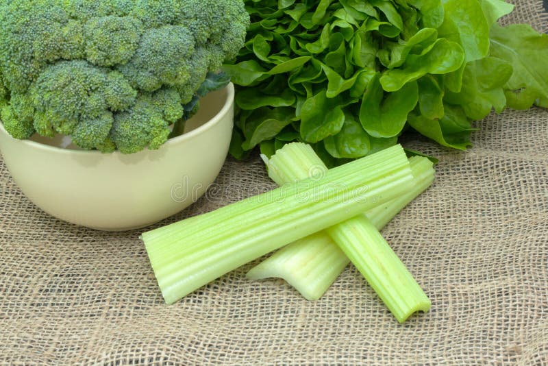 Green vegetables. whole broccoli in a bowl with lettuce and celery on the tablecloth. Green vegetables. whole broccoli in a bowl with lettuce and celery on the tablecloth