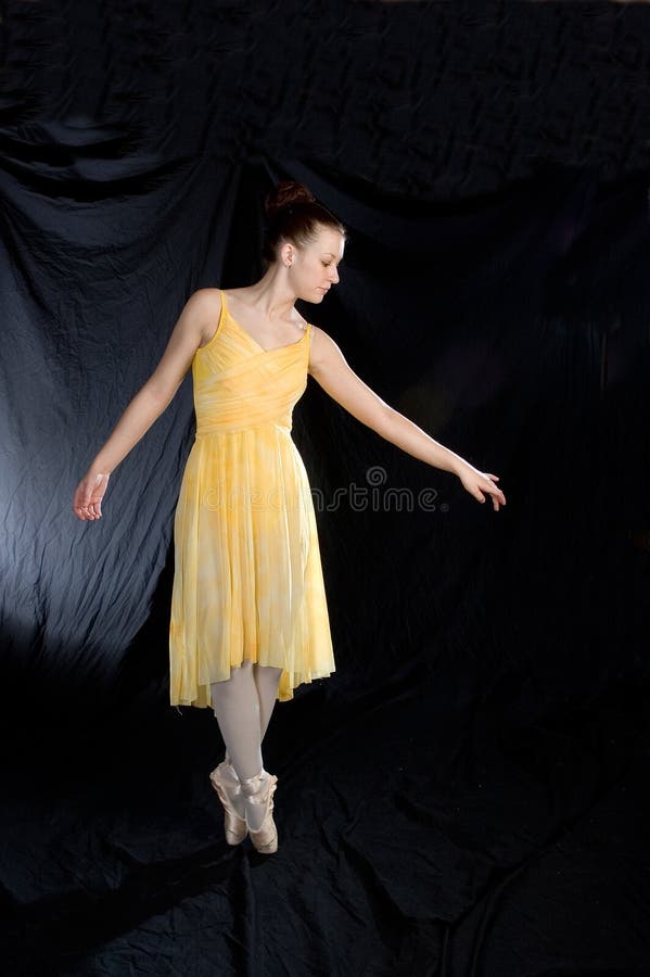 A ballerina stands on pointe in a yellow costume. A ballerina stands on pointe in a yellow costume