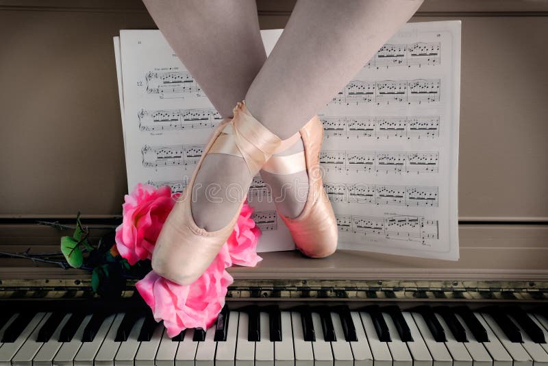A ballerinas legs rest on piano wearing pointe slippers. A ballerinas legs rest on piano wearing pointe slippers.