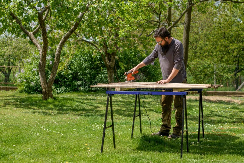 花园中白种成年男子打磨木板 DIY家居装修，修复，木工概念