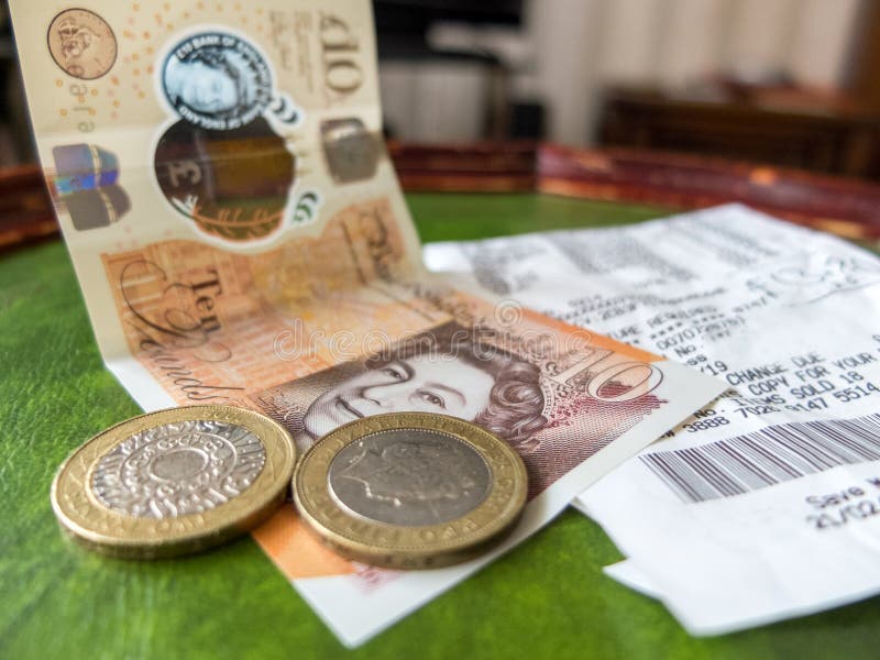 Ten pound note with two £2 coins and supermarket shopping receipt. Ten pound note with two £2 coins and supermarket shopping receipt