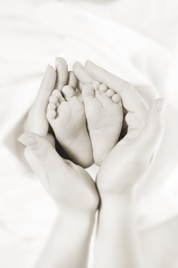 Mother holds baby feet in her hands. Closeup. Monochrome. Mother holds baby feet in her hands. Closeup. Monochrome