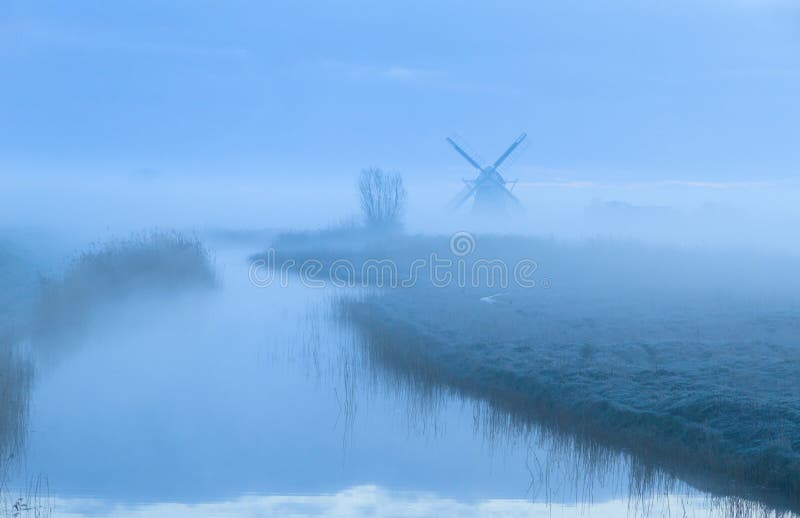 Foggy dawn at the water and a windmill in the Dutch countryside. Foggy dawn at the water and a windmill in the Dutch countryside.