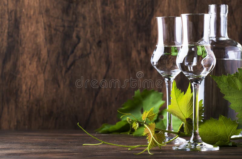 Grape vodka, pisco - traditional Peruvian strong alcoholic drink in elegant glasses  on vintage wooden table, copy space. Grape vodka, pisco - traditional Peruvian strong alcoholic drink in elegant glasses  on vintage wooden table, copy space