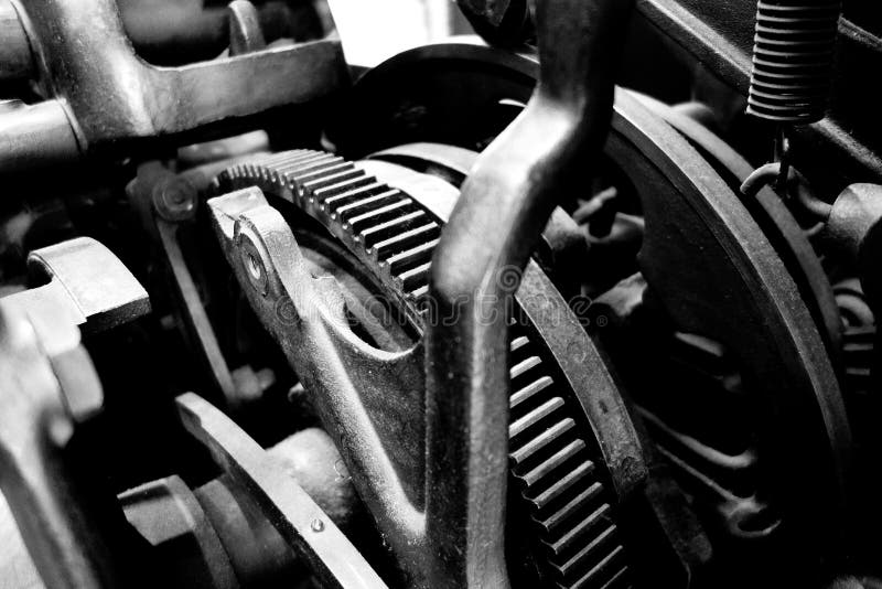 A macro black and white image of the insides of an old time machine with metal toothed gears and springs adjustable moving parts. A macro black and white image of the insides of an old time machine with metal toothed gears and springs adjustable moving parts.