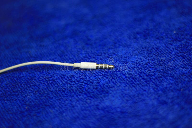 Earphones 3.5mm Audio Jack on blue microfiber cloth. Earphones 3.5mm Audio Jack on blue microfiber cloth