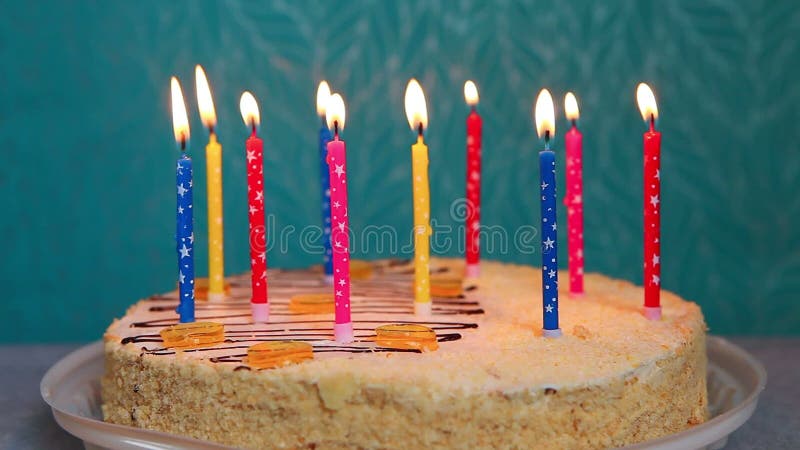 蓝色背景中燃烧彩色蜡烛的生日蛋糕